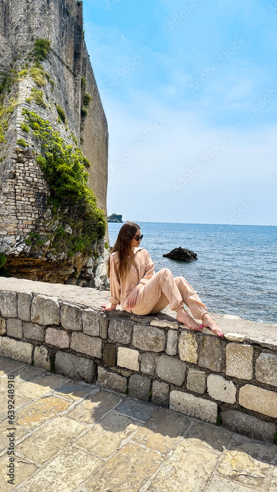 Beautiful woman sits on the rock at the sea