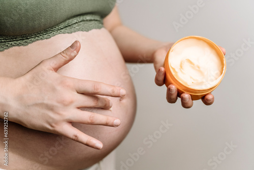 A pregnant woman uses a cream for stretch marks. Prevention of stretch marks on the abdomen and legs, skin care during pregnancy photo