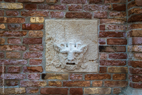 Una buca delle lettere a forma di maschera sul muro di una chiesa di Venezia photo