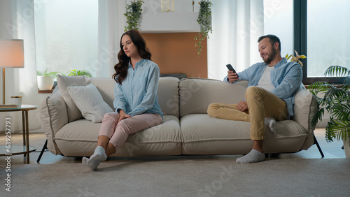Caucasian couple at home couch sofa family problem relationship trouble offended woman girlfriend wife upset offense at husband boyfriend man addict with mobile phone social media laughing browsing