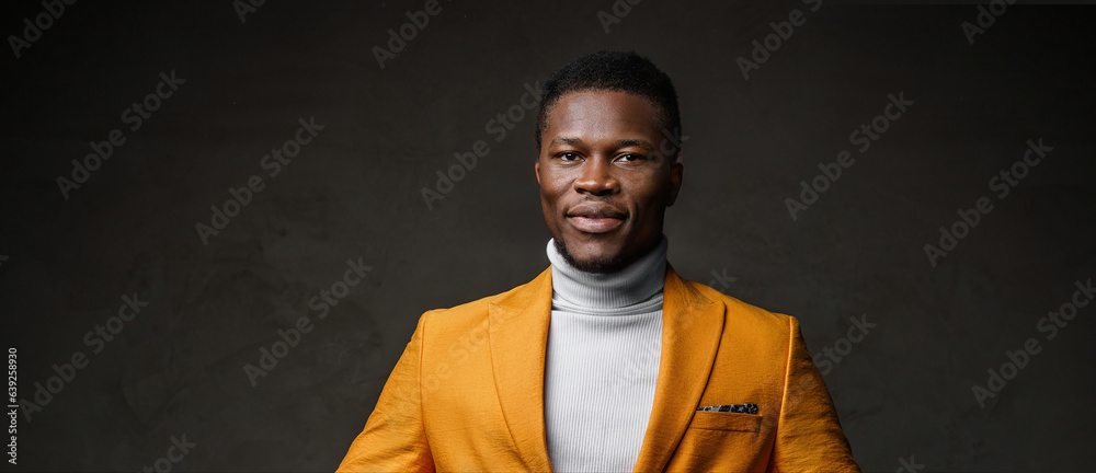 Portrait of a smartly dressed black man in a yellow blazer with short hair against a dark backdrop Portrait of a smartly dressed black man in a yellow blazer with short hair against a dark backdrop