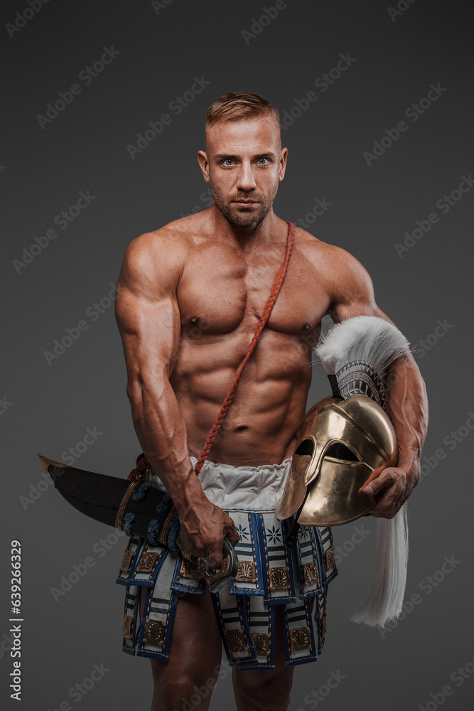 Ancient Greek hoplite warrior, displaying his muscular physique and strength as he stands poised with a helmet and spear, surrounded by a minimalist grey setting