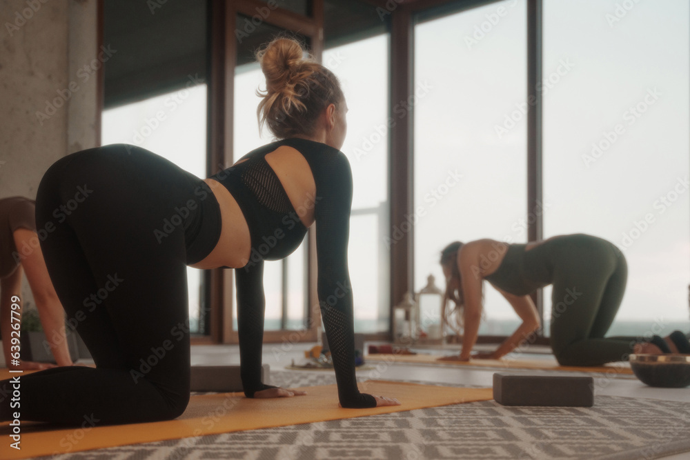 Group of girls practicing yoga and meditation in a city apartment with panoramic views