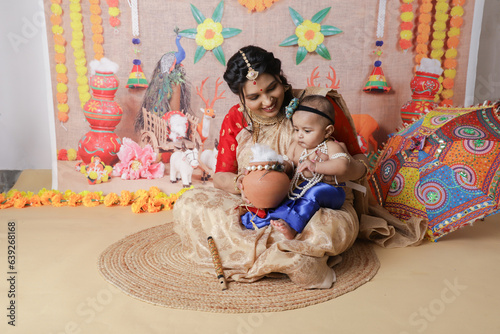 Janmashtami Concept. Mother sitting with her cute baby boy dressed up as little krishna. photo