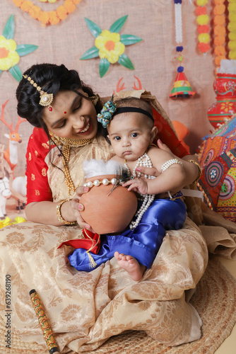 Janmashtami Concept. Mother sitting with her cute baby boy dressed up as little krishna.
