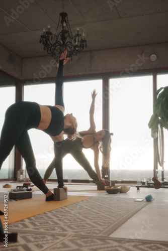 Group of girls practicing yoga and meditation in a city apartment with panoramic views