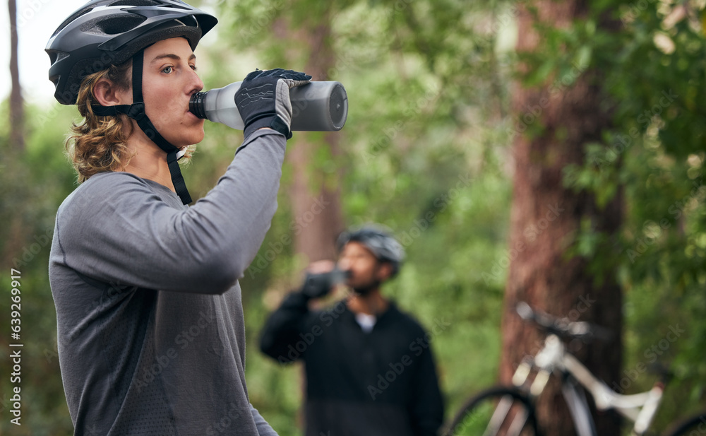 Forest, cyclist and men drinking water, exercise and tired with workout, refreshing and fitness. Healthy people, athlete and bikers in the woods, hydration and outdoor with liquid, bottles and helmet