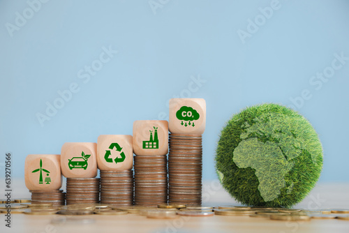 Green Globe with world map and green business icons on wooden cube place on coins stack.Concept of Green business, finance and sustainability investment. Carbon credit. ESG, Co2, SDGs, Net Zero.