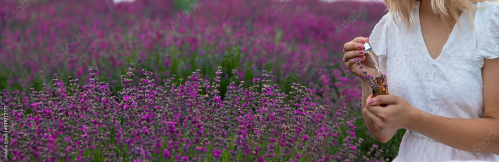 Woman holding bottle with natural essential oil in lavender field. Selective focus Woman holding bottle with natural essential oil in lavender field. Selective focus