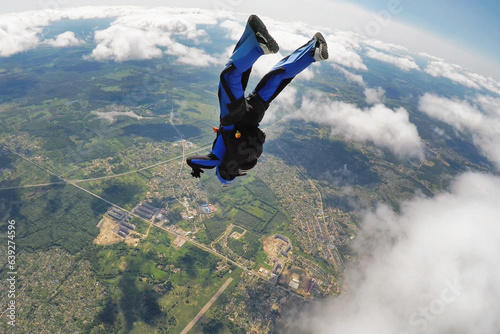 Skydiver falling headdown over the clouds
