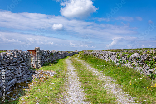Old dirt green patch surrounded by stone walls on a beautiful sunny day with blue sky and white clouds