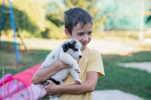 adorable portrait of amazing healthy and happy black and white border collie puppy in the hand of cute little boy
