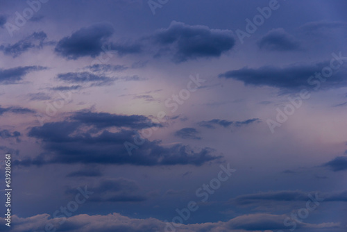 Fototapeta Naklejka Na Ścianę i Meble -  Niebo pokryte cienką warstwą ciemnych szarych chmur. Przez chmury widać przenikające światło słoneczne.
