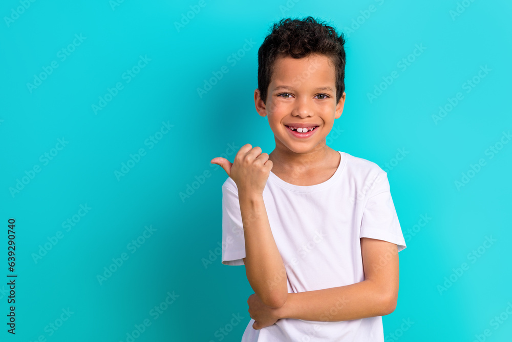 Portrait of cheerful friendly little boy beaming smile direct thumb finger empty space isolated on turquoise color background Portrait of cheerful friendly little boy beaming smile direct thumb finger empty space isolated on turquoise color background