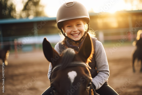 Obraz na plátne Happy girl kid at equitation lesson looking at camera while riding a horse, wear