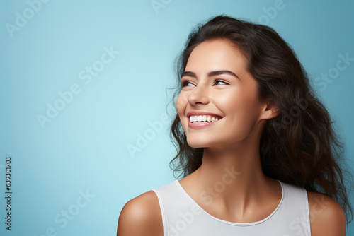 Young woman with beautiful smile on light blue background. Dental clinic. Orthodontics. Copy space.