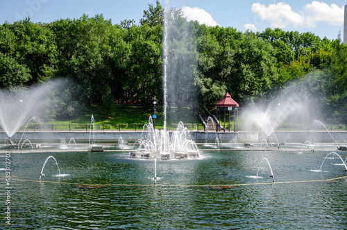 A pond with working fountains, surrounded by a monument of trees and lawn
