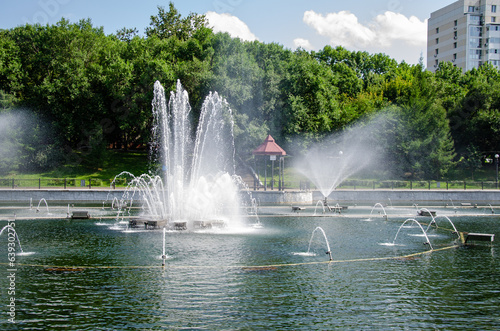 A pond with working fountains, surrounded by a monument of trees and lawn