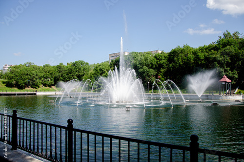 A pond with working fountains, surrounded by a monument of trees and lawn