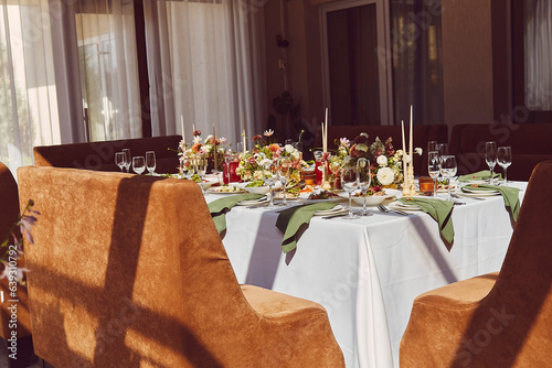 Restaurant aesthetic festive table setting, flowers arrangement under sunlight shadows.