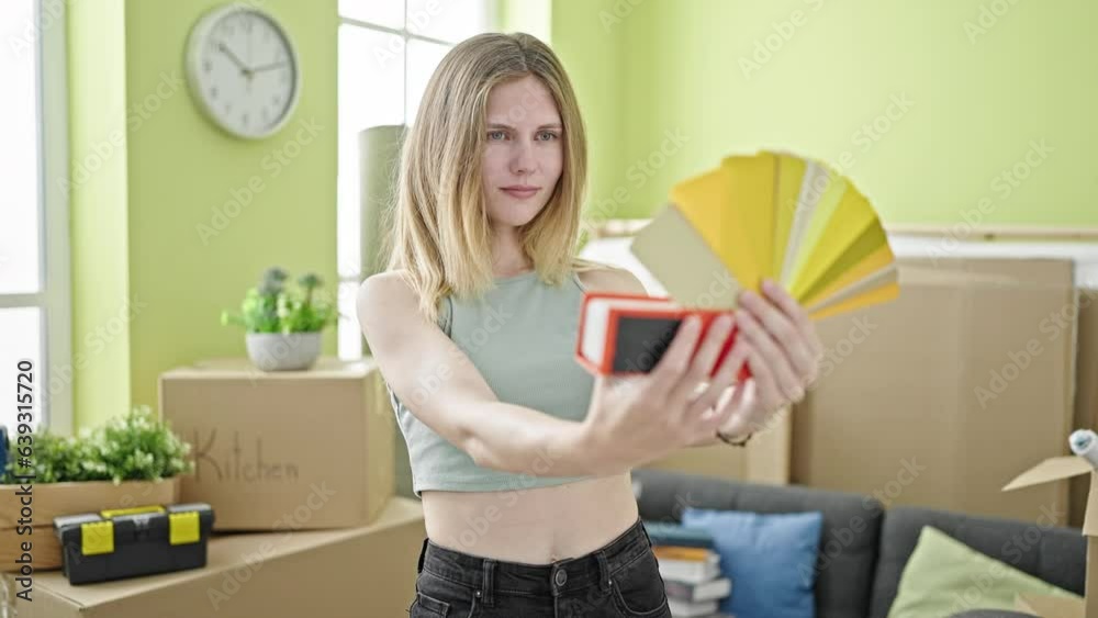 Young blonde woman holding color test thinking at new home Young blonde woman holding color test thinking at new home