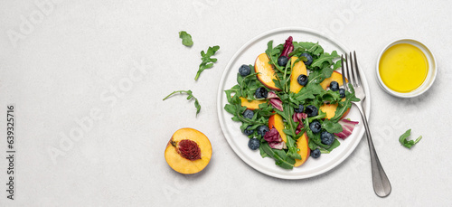 Peach arugula blueberry salad in plate on white background. Delicious fruit salad