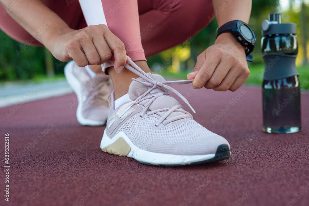 Closeup of woman tying shoe laces. Female sport fitness runner getting ready for jogging outdoors