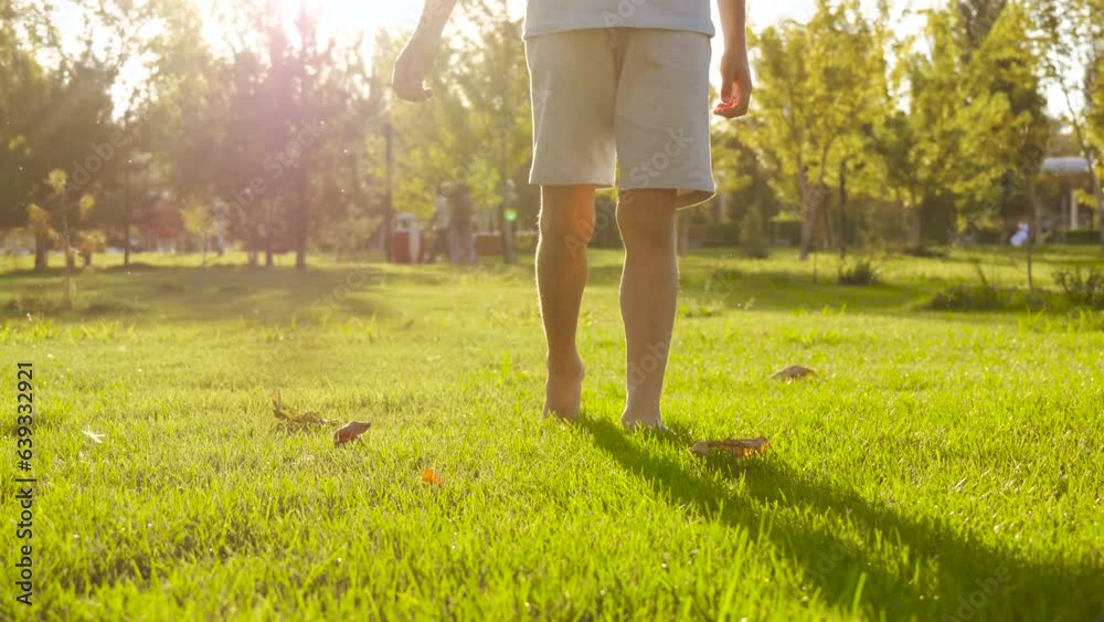 The Kid Feet Are Walking On The Green Grass In Close up A Boy Walks the-kid-feet-are-walking-on-the-green-grass-in-close-up-a-boy-walks