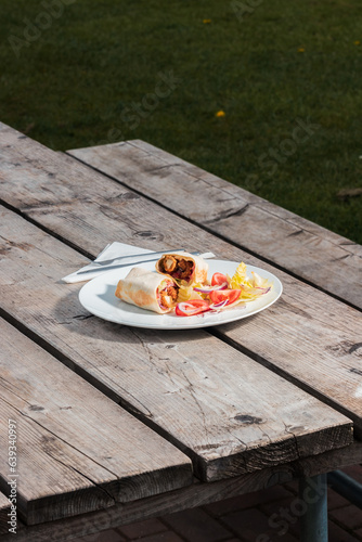 A quesadilla dish on a white plate at an outdoor café on a wooden table, clean cutlery and napkin