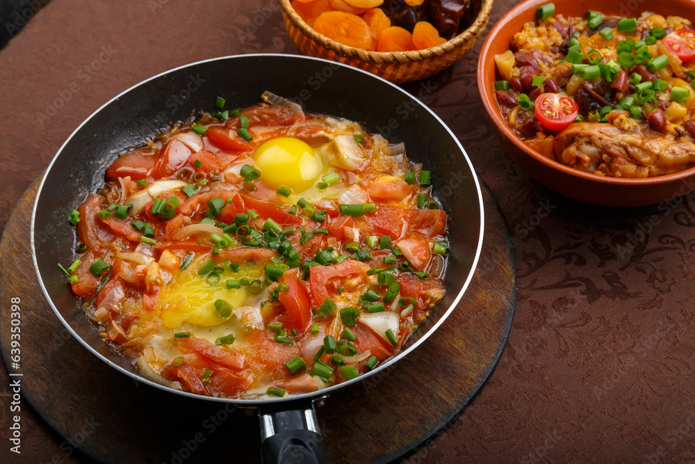 hot shakshuka in a frying pan sprinkled with green onions on the Shabbat table.