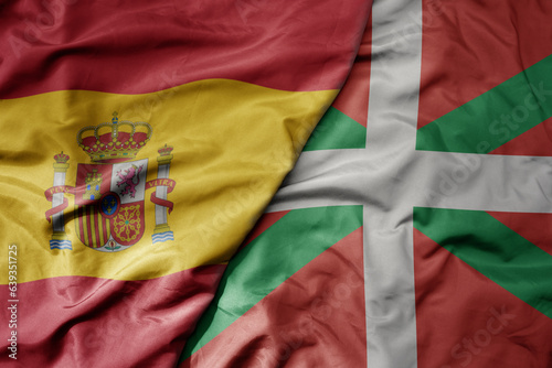 big waving national colorful flag of spain and national flag of basque country .