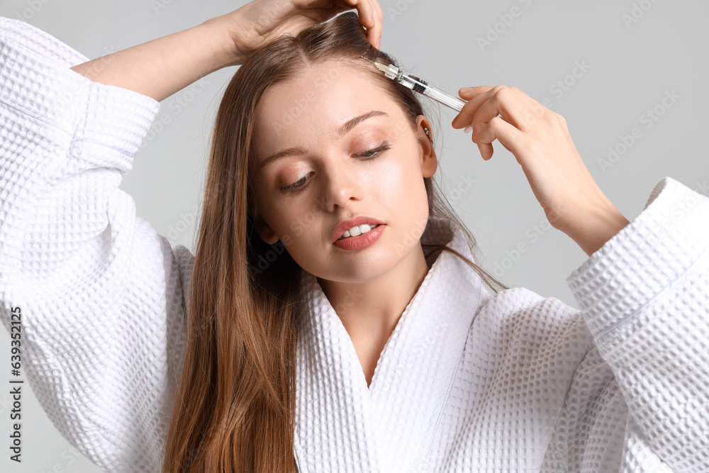 Naklejka premium Woman with hair loss problem giving herself injection on light background