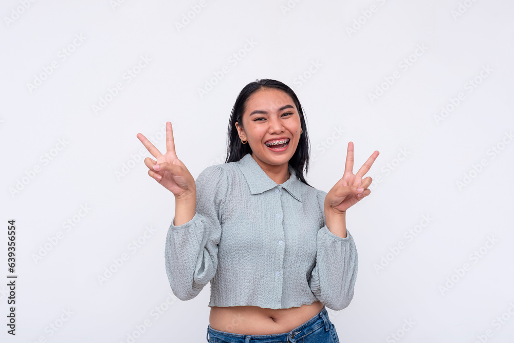 A vivacious young asian woman makes a double peace sign. Feeling upbeat and elated. Isolated on a white background. A vivacious young asian woman makes a double peace sign. Feeling upbeat and elated. Isolated on a white background.