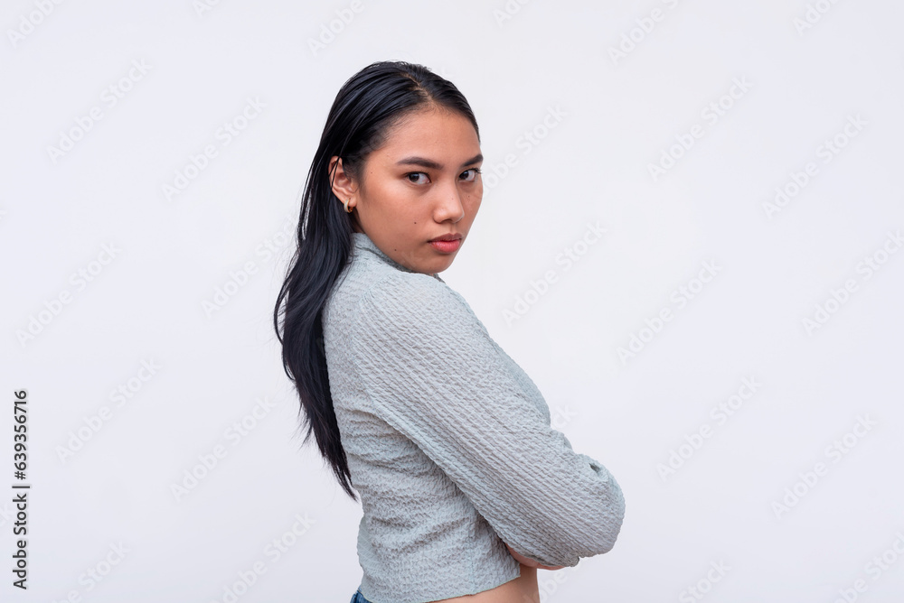 Fototapeta premium A pensive and bossy young asian woman with arms crossed. With a poker faced expression and formidable gaze looking at the camera. Isolated on a white background.