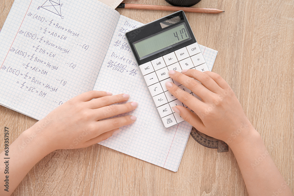 Woman working with calculator on wooden table, closeup Woman working with calculator on wooden table, closeup