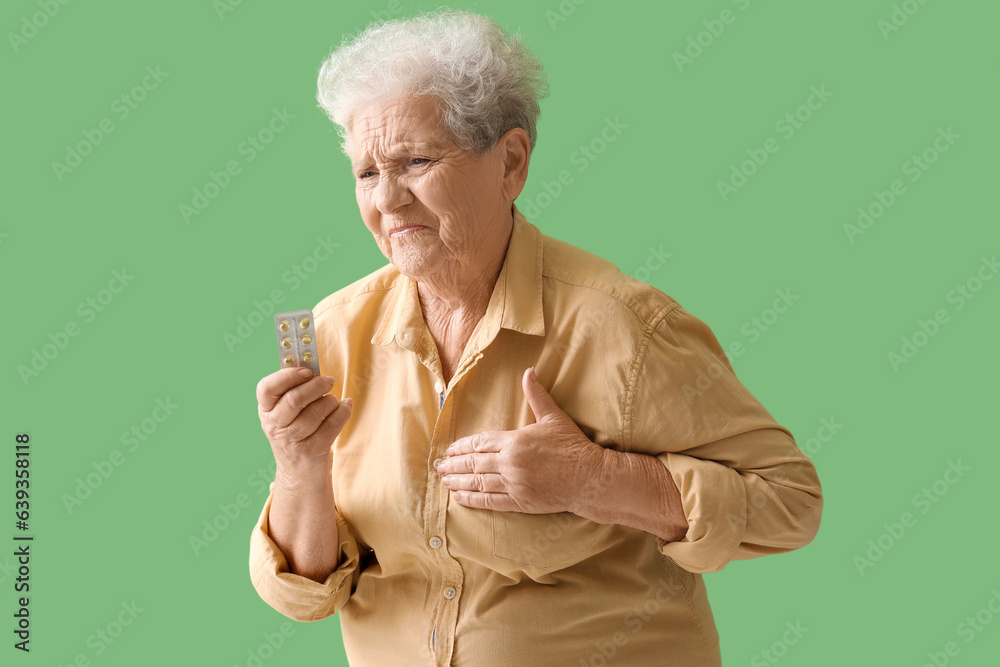 Elderly woman with pills having heart attack on green background Elderly woman with pills having heart attack on green background