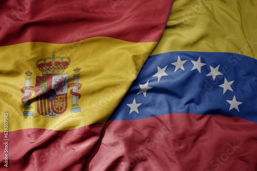 big waving national colorful flag of spain and national flag of venezuela .