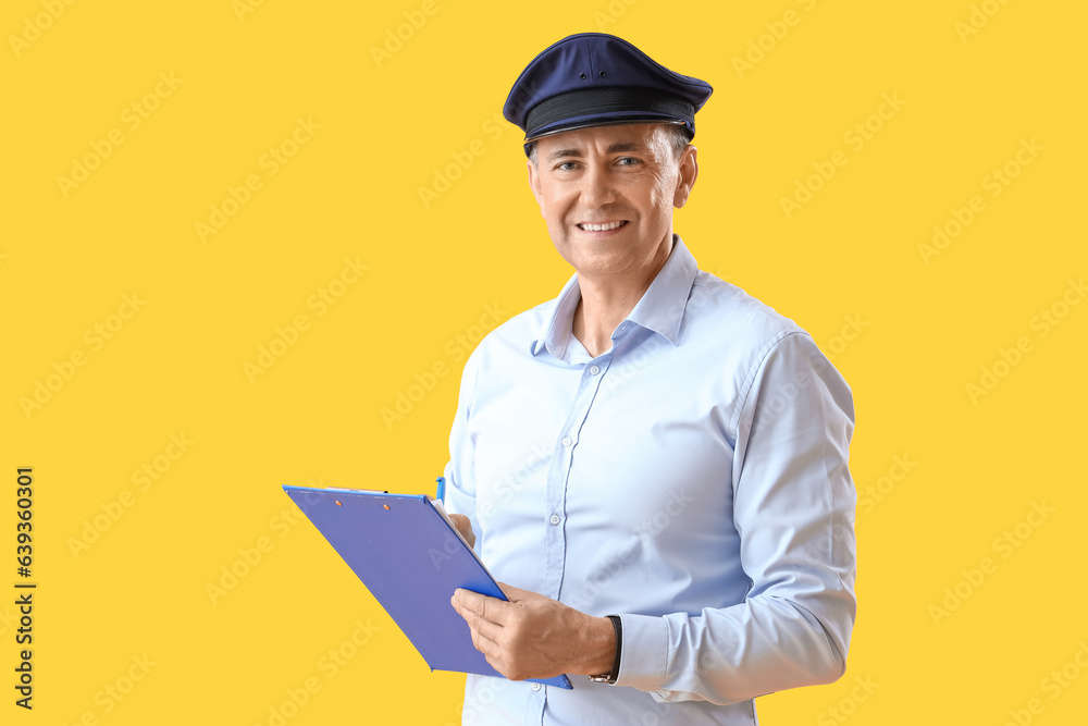 Mature postman with clipboard on yellow background Mature postman with clipboard on yellow background