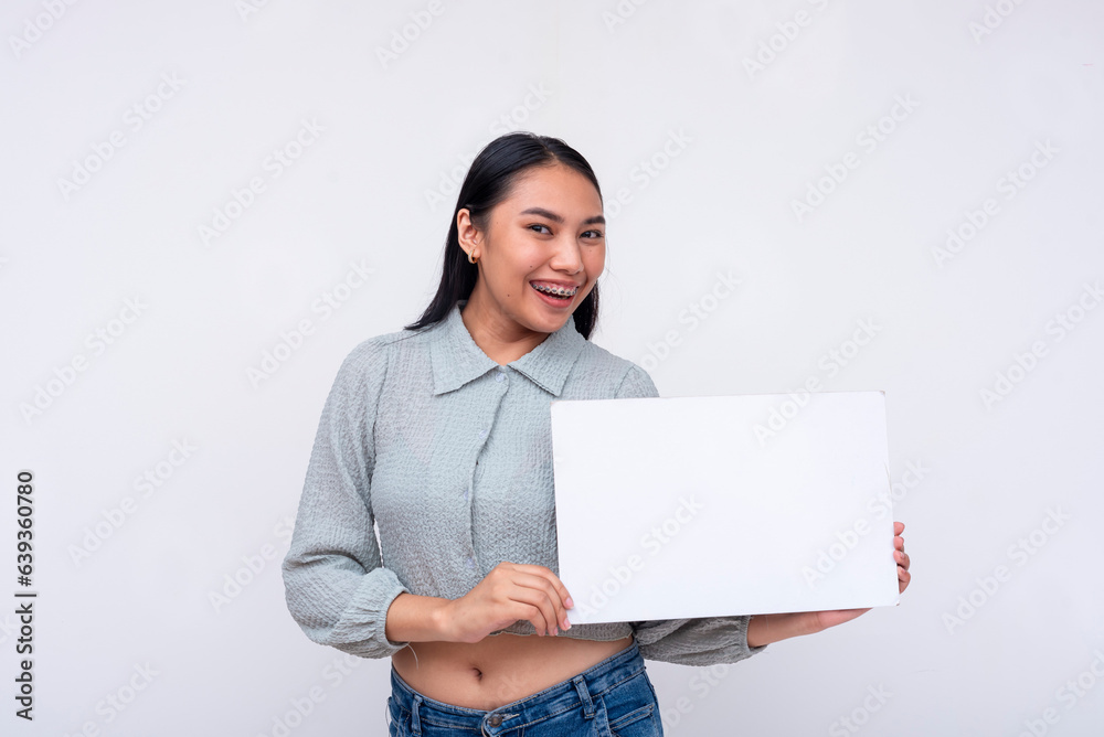 A smart young Asian woman smiling pleasantly while holding a white blank signage. Isolated on a white background. A smart young Asian woman smiling pleasantly while holding a white blank signage. Isolated on a white background.