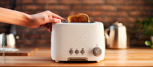 Man operating white toaster on wooden counter in kitchen