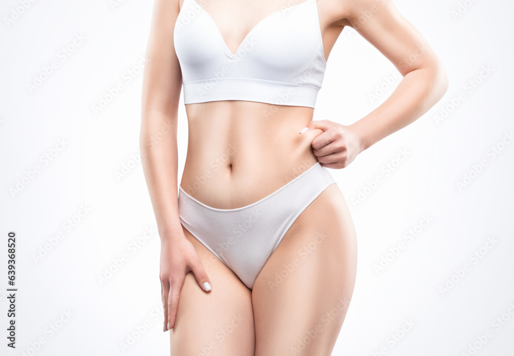 Girl pulls the skin on the abdomen and on the hips showing the body fat. Treatment and disposal of excess weight, the deposition of subcutaneous fat.