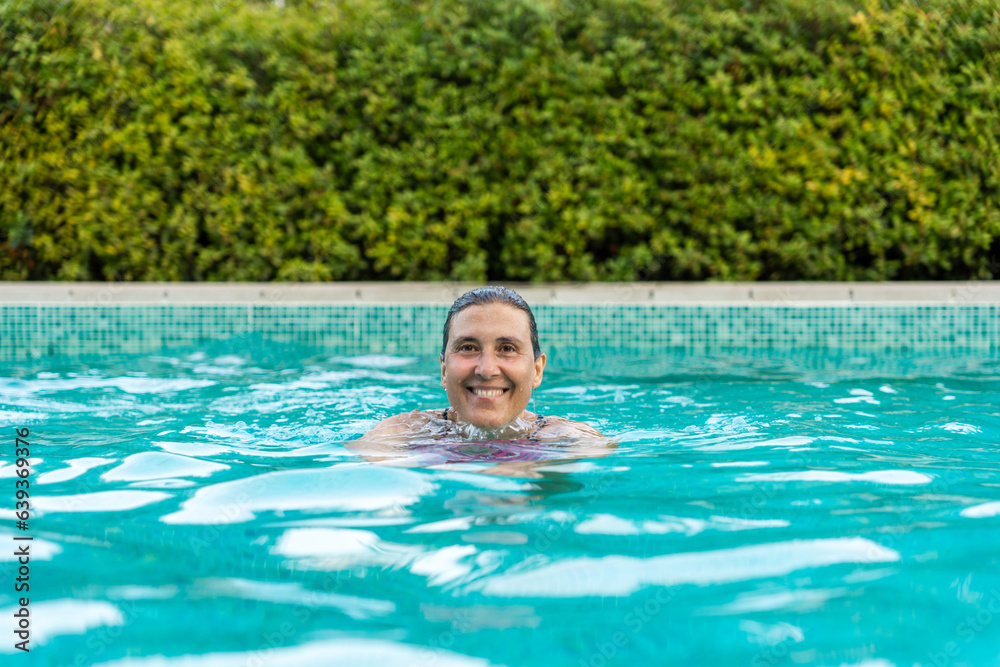 A  smiling woman swimming in a pool.