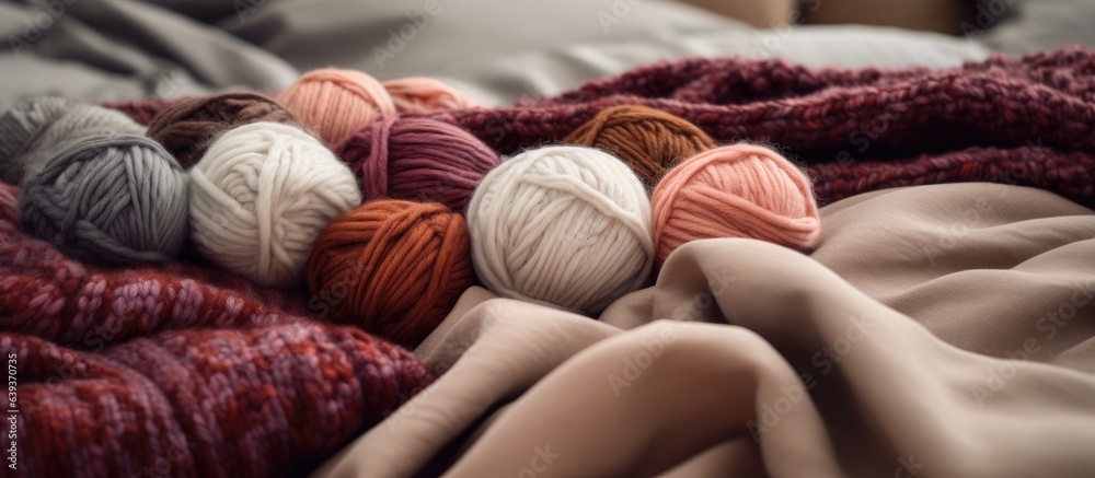 Yarn balls and a wool blanket on the bedspread - obrazy, fototapety, plakaty 