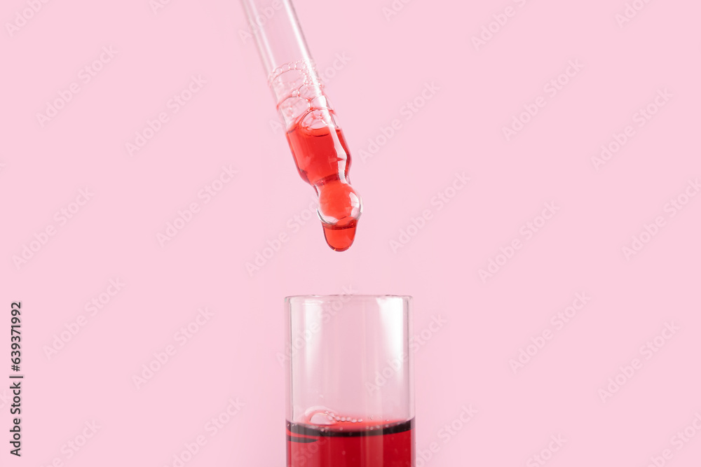 Pipette dripping sample into test tube on pink background, closeup Pipette dripping sample into test tube on pink background, closeup