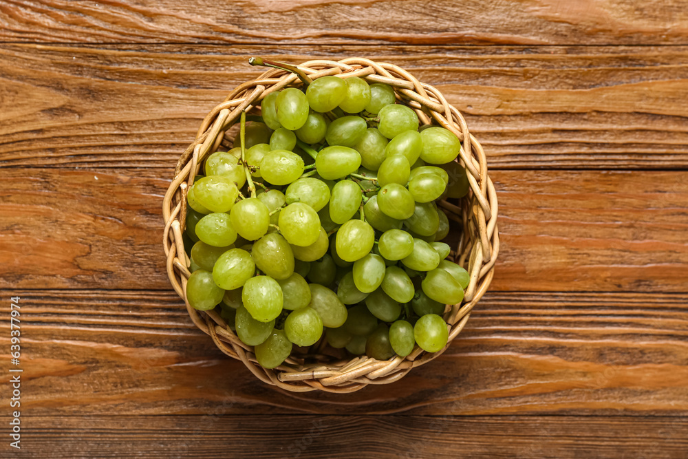 Wicker bowl with sweet green grapes on wooden background Wicker bowl with sweet green grapes on wooden background