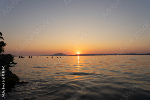 sunset at Lake Balaton with silhouette of night bathing people and the north part mountains in the background