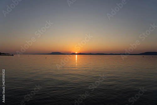 sunset at Lake Balaton with silhouette of night bathing people and the north part mountains in the background