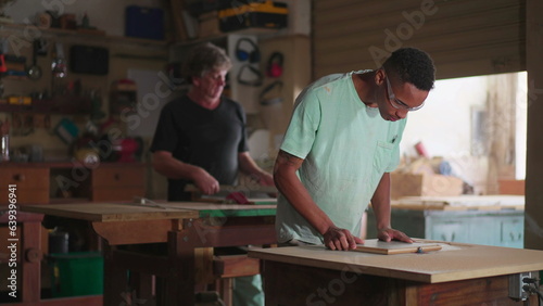 Candid Carpentry Workshop Scene of Master Carpenter and Apprentice at Work. Concentrated workers engaged with job occupation