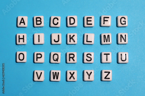 English alphabet. Beads white tiles on a blue background.