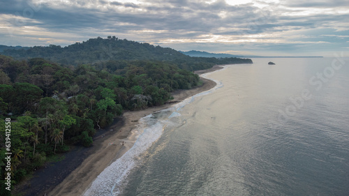 Drone view of beautiful jungle caribbean beach with nice surf close to Playa Cocles and Puerto Viejo in Costa rica. View towards the trees. hazy sea and spray.